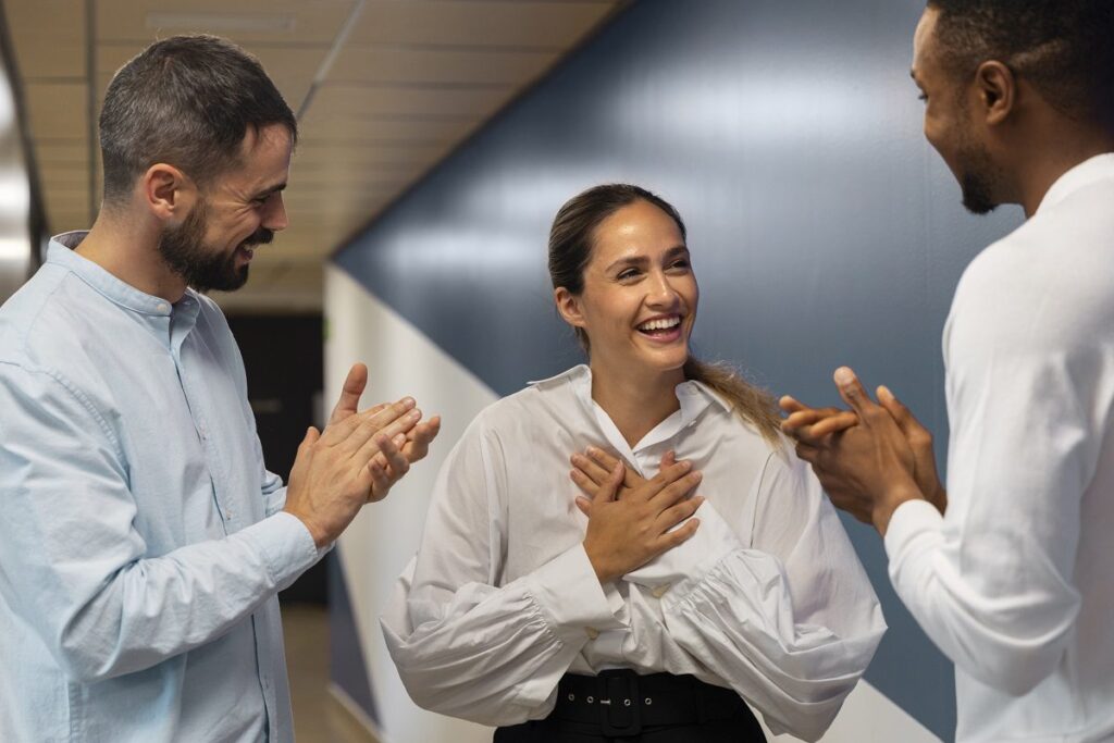 Três funcionários da GR Assessoria Contábil e Tributária sorriem em um ambiente de trabalho positivo e acolhedor.